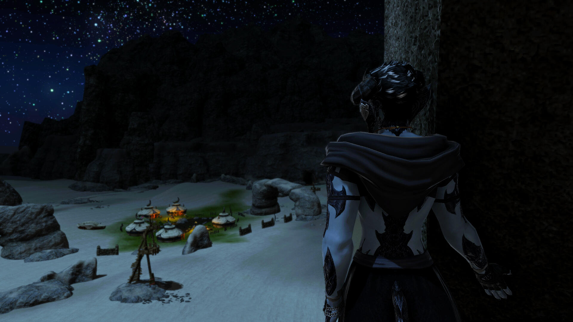 A man in a hooded shawl stands near a large stone, facing away from the camera. He has dark scales across his arms and down his spine, and he looks out at a village of tents below him in an oasis.